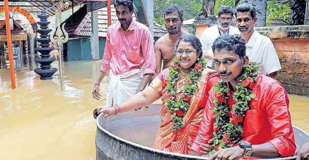 Alluvione India. I giovani sposi si spostano su un enorme vaso da cucina