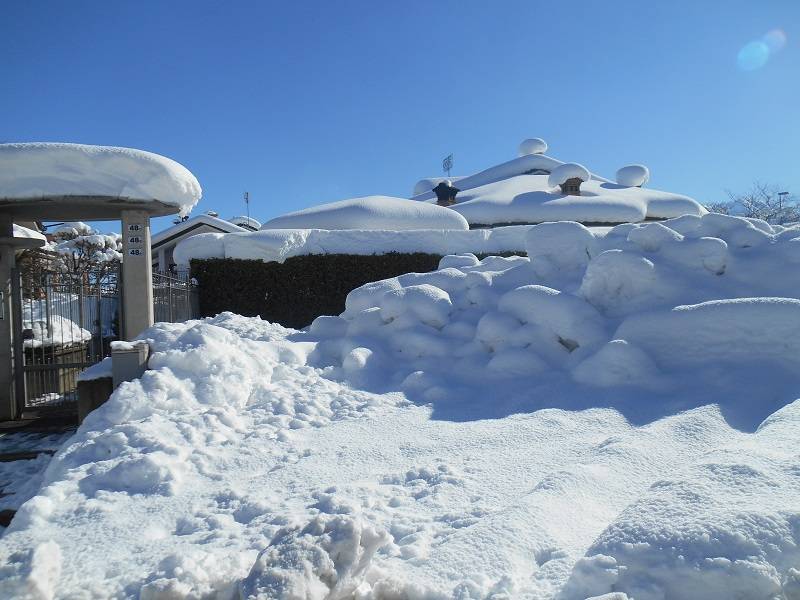 Villetta magicamente sommersa da una candida coltre di neve sotto un sole accecante