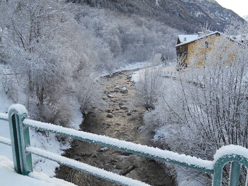 Colori del sole e della neve sul torrente invernale a Prazzo